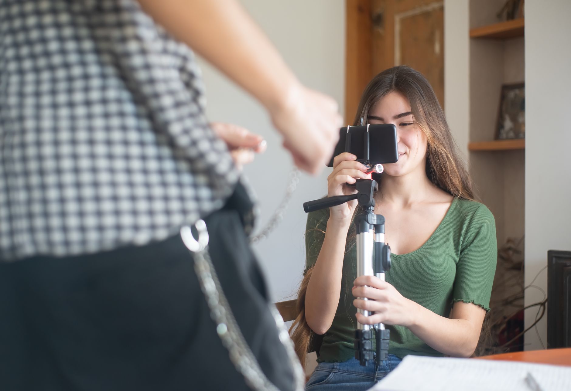 Jeune femme filmant un contenu vidéo chez elle avec un smartphone monté sur trépied.