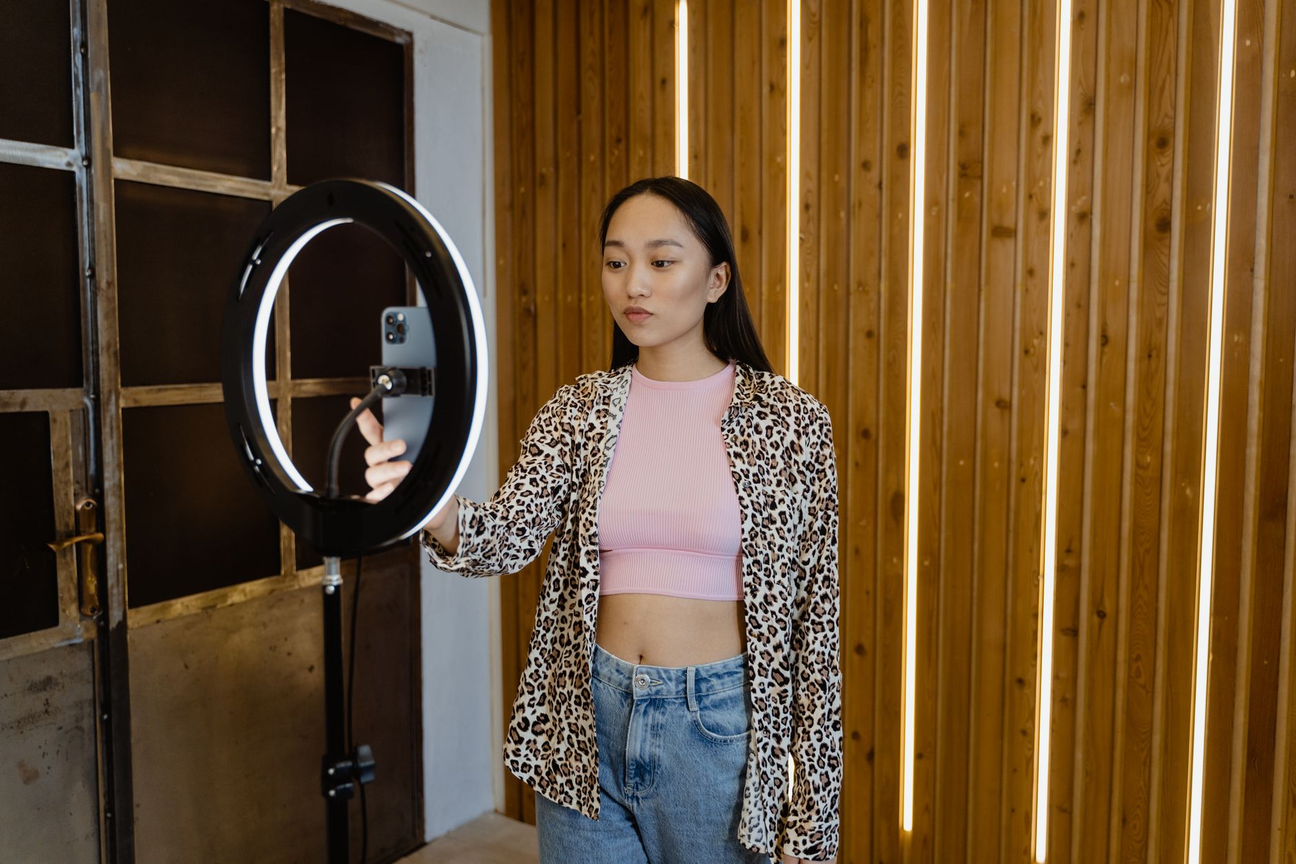 Influenceuse asiatique filmant un vlog avec un anneau lumineux dans un intérieur soigné.