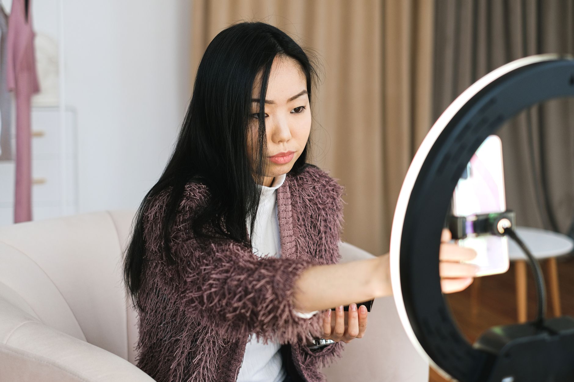Une créatrice filme un vlog chez elle avec un smartphone et un anneau lumineux, illustration d'un tournage UGC à domicile.