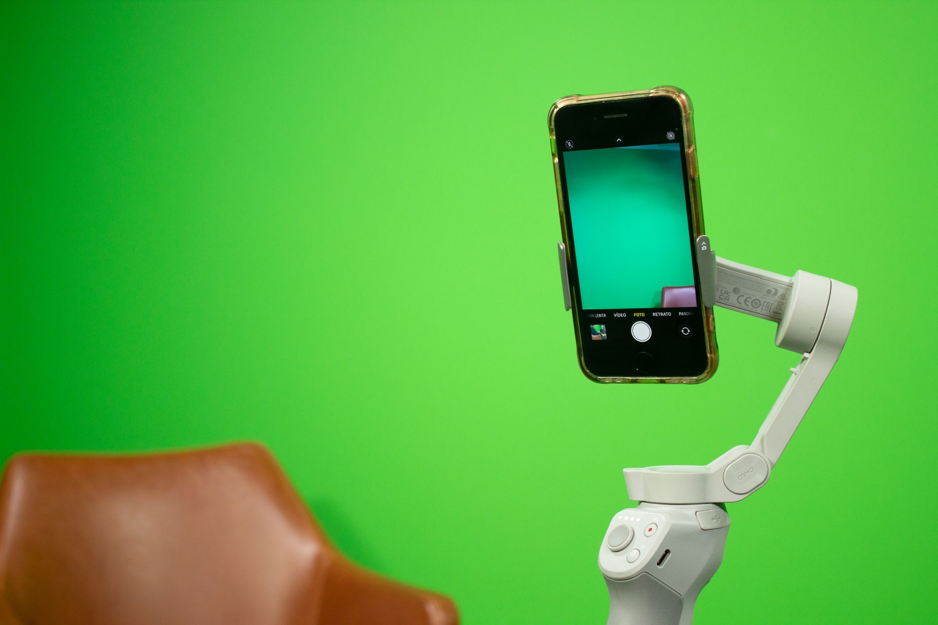 Smartphone monté sur un stabilisateur devant un fond vert, installation pour la production vidéo.